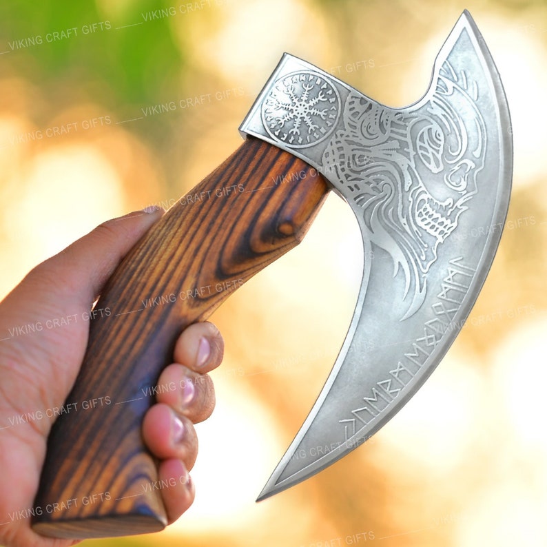 May include: A silver Viking axe with a wooden handle. The axe head features a detailed design of a wolf's head and runes. The handle is made of dark wood with a grain pattern.