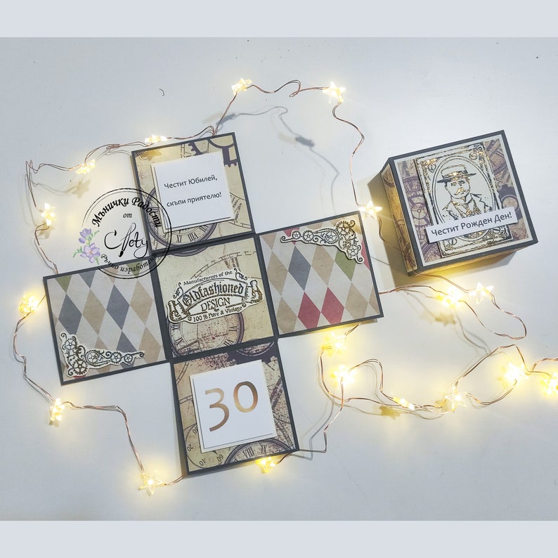 May include: A brown and black explosion box with a vintage design. The box has a clock face on one side, a diamond pattern on another, and a number 30 on a third side. The box is decorated with gold accents and has the text "Oldfashioned Design" on one side. The box is open and the inside is visible. The text "Cheстит Юбилей, скъпи приятелю!" is visible on one side of the box. The text "Честит Рожден Ден!" is visible on another side of the box.