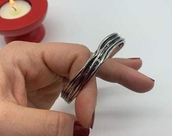 May include: A silver bracelet with a woven design. The bracelet is made of multiple strands of metal that are twisted together.