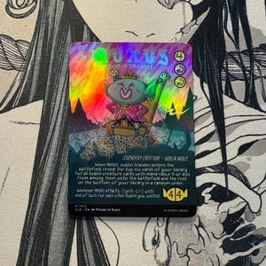 May include: A holographic trading card featuring the character Muxus, Goblin Grandee, sitting on a throne atop a pile of skulls. The card displays the text Muxus, Goblin Grandee, Legendary Creature - Goblin Noble, and includes game rules text and a 4/4 power and toughness rating in the bottom right corner.