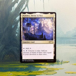 May include: A rectangular Magic: The Gathering trading card titled Nykthos, Shrine to Nyx. The card features a fantasy illustration of a glowing temple structure under a starry sky, with text detailing its function as a legendary land card.