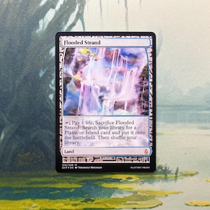May include: A rectangular trading card titled Flooded Strand featuring an illustration of cascading waterfalls. The card text includes game instructions, the classification Land, and the set code 016/045 M. The border is black with white decorative patterns.
