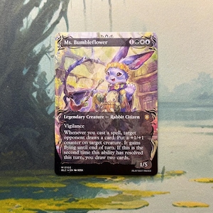 May include: A Magic: The Gathering trading card titled Ms. Bumbleflower, a Legendary Creature Rabbit Citizen. The artwork depicts a purple rabbit character with a yellow floral crown, wearing a tan outfit, holding a staff. Text includes card abilities.