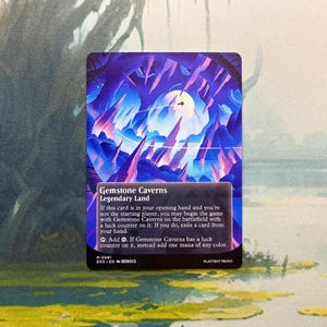 May include: A rectangular trading card titled Gemstone Caverns, featuring a vibrant illustration of jagged purple and blue crystal formations under a glowing moon. The card text details the Legendary Land rules and abilities in white font.