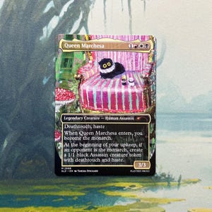 May include: A Magic: The Gathering trading card titled Queen Marchesa featuring a black cat with large yellow eyes sitting on a pink and white striped chair. The card text includes Deathtouch, haste, and the monarch mechanic details.