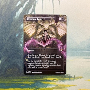 May include: A rectangular trading card titled Demonic Tutor featuring a dark fantasy illustration of a horned figure with wings hovering over a person reading a glowing pink book. The card text includes Sorcery, game instructions, and flavor text.