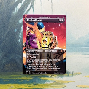 May include: A rectangular trading card titled The Soul Stone featuring a purple-skinned character wearing a gold gauntlet with glowing stones. The card text includes Legendary Artifact, Indestructible, and game mechanics against a dark red background.