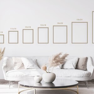 Pu&ograve; includere: Un divano bianco con cuscini in un soggiorno. La parete dietro il divano presenta una serie di cornici vuote con le dimensioni indicate sopra ogni cornice: 8x10, 11x14, 12x16, 12x18, 16x20, 18x24 e 24x36.