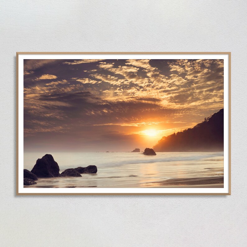Costa Rica art print of a beautiful beach sunset at Manuel Antonio, Quepos. This photograph captures the warm hues of the sun as it sets over the Pacific, casting a golden glow on the sand and the waves.