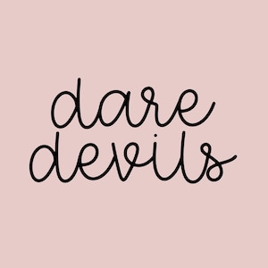 May include: Black and white handwritten text that reads "dare devils" on a light pink background.