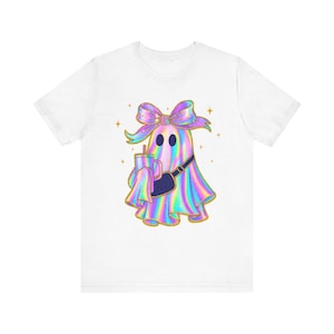 Op de afbeelding: Wit T-shirt met een cartoongeest in een holografisch ontwerp, met een strik, heuptas en een drankje. De geest heeft een gouden omtrek en is omgeven door gouden sterren. Een leuk, grillig ontwerp.