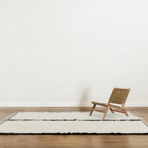 Handmade Moroccan wool rug featuring a minimalist black and white design. Ethically crafted by Berber artisans in Morocco using 100% natural wool. Thick, plush, and ultra-soft, this Beni Ourain-style carpet is perfect for modern, Scandinavian, and bohemian interiors. Ideal for living rooms, bedrooms, and luxury home decor. Available in custom sizes. Authentic tribal craftsmanship with eco-friendly materials. Free worldwide shipping with FedEx Express.