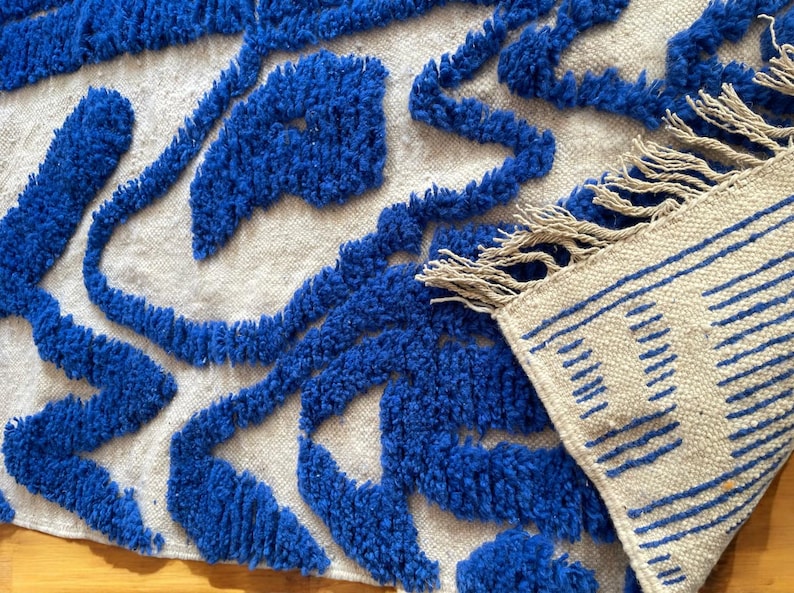 A vintage Moroccan wool rug with a bold blue abstract design handwoven on a neutral beige background, featuring plush texture and traditional fringed edges Vintage Rug, Moroccan Rug Wool Rug Abstract Rug Handwoven Rug Blue Rug Bold Design Modern Rug