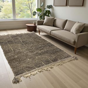Handwoven Moroccan rug made from 100% natural wool in Travertine and White tones. Its rich texture and neutral color palette make it the perfect statement piece for modern, minimalist, or boho interiors. Crafted by Amazigh artisans in the Atlas Mountains, this rug combines traditional Moroccan weaving with a soft, earthy design. Ideal for living rooms, bedrooms, or cozy reading spaces, it brings warmth and timeless elegance to your home.