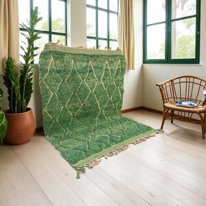 Green Moroccan wool rug with cream diamond lattice pattern, handmade in Beni Ourain style. Styled in a bright modern boho room with plants, rattan furniture, and natural light. The rug has a plush texture, tribal design, and fringe details, making it perfect for earthy, creative, or minimalist interiors. Crafted by Berber artisans, it's soft, thick, and ethically made using traditional weaving techniques.