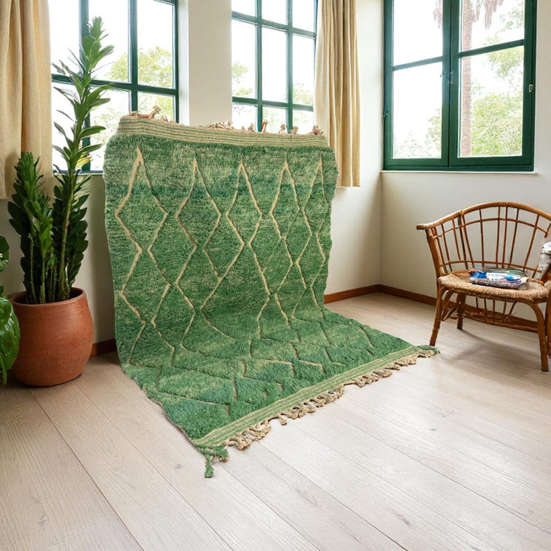 Green Moroccan wool rug with cream diamond lattice pattern, handmade in Beni Ourain style. Styled in a bright modern boho room with plants, rattan furniture, and natural light. The rug has a plush texture, tribal design, and fringe details, making it perfect for earthy, creative, or minimalist interiors. Crafted by Berber artisans, it's soft, thick, and ethically made using traditional weaving techniques.