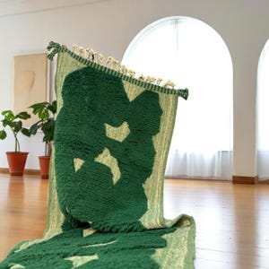 Extra-long Moroccan runner rug in deep green with bold organic patterns and beige wool base. This handcrafted Beni Ourain wool carpet is perfect for hallways, corridors, and modern interiors needing a unique, earthy touch. Made by Berber artisans using natural wool, it combines luxury softness and geometric structure. Ideal for minimalist, boho, or Japandi-style homes.