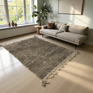 Handwoven Moroccan rug made from 100% natural wool in Travertine and White tones. Its rich texture and neutral color palette make it the perfect statement piece for modern, minimalist, or boho interiors. Crafted by Amazigh artisans in the Atlas Mountains, this rug combines traditional Moroccan weaving with a soft, earthy design. Ideal for living rooms, bedrooms, or cozy reading spaces, it brings warmth and timeless elegance to your home.