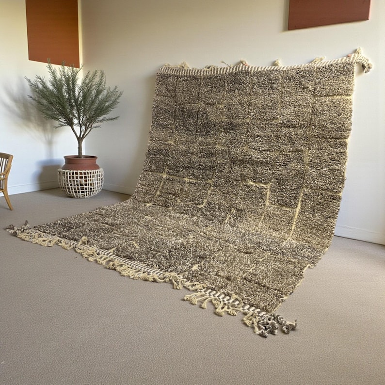 Handwoven Moroccan rug made from 100% natural wool in Travertine and White tones. Its rich texture and neutral color palette make it the perfect statement piece for modern, minimalist, or boho interiors. Crafted by Amazigh artisans in the Atlas Mountains, this rug combines traditional Moroccan weaving with a soft, earthy design. Ideal for living rooms, bedrooms, or cozy reading spaces, it brings warmth and timeless elegance to your home.