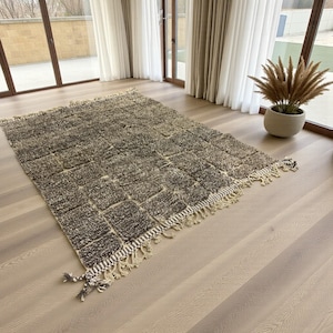 Handwoven Moroccan rug made from 100% natural wool in Travertine and White tones. Its rich texture and neutral color palette make it the perfect statement piece for modern, minimalist, or boho interiors. Crafted by Amazigh artisans in the Atlas Mountains, this rug combines traditional Moroccan weaving with a soft, earthy design. Ideal for living rooms, bedrooms, or cozy reading spaces, it brings warmth and timeless elegance to your home.
