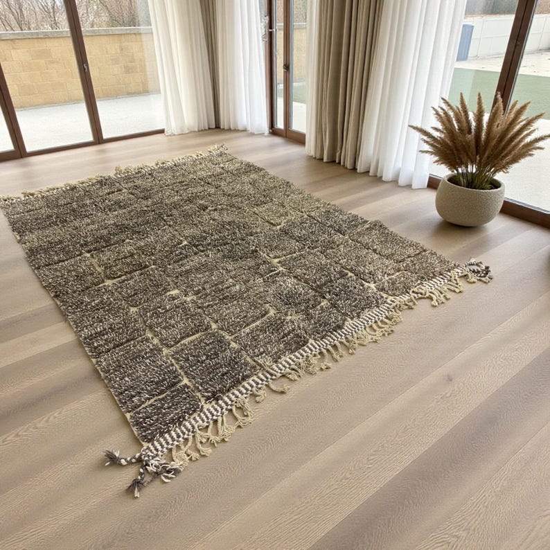 Handwoven Moroccan rug made from 100% natural wool in Travertine and White tones. Its rich texture and neutral color palette make it the perfect statement piece for modern, minimalist, or boho interiors. Crafted by Amazigh artisans in the Atlas Mountains, this rug combines traditional Moroccan weaving with a soft, earthy design. Ideal for living rooms, bedrooms, or cozy reading spaces, it brings warmth and timeless elegance to your home.