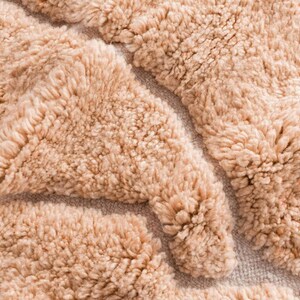 Minimalist Moroccan rug in a warm peach shade with modern geometric lines, perfect for Pinterest-inspired interiors. Handmade soft wool texture for cozy bedroom decor, stylish living rooms, or aesthetic content creator setups. This rug screams soft luxury, quiet comfort, and effortless viral style. Ideal for boho homes, apartment styling, and Instagram-worthy vibes.