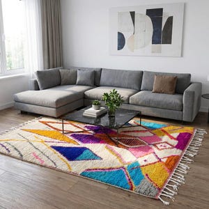 Authentic handmade Moroccan Boujaad rug featuring bold geometric diamond patterns in vibrant multicolor — electric blue, fuchsia pink, orange, yellow and purple on ivory wool background. Hand-knotted by Berber artisans in Morocco using natural wool. Perfect boho statement rug for living room, bedroom or dining room. One-of-a-kind colorful area rug with traditional fringe.