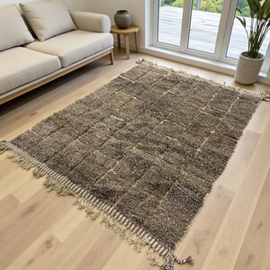 Handwoven Moroccan rug made from 100% natural wool in Travertine and White tones. Its rich texture and neutral color palette make it the perfect statement piece for modern, minimalist, or boho interiors. Crafted by Amazigh artisans in the Atlas Mountains, this rug combines traditional Moroccan weaving with a soft, earthy design. Ideal for living rooms, bedrooms, or cozy reading spaces, it brings warmth and timeless elegance to your home.