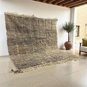 Handwoven Moroccan rug made from 100% natural wool in Travertine and White tones. Its rich texture and neutral color palette make it the perfect statement piece for modern, minimalist, or boho interiors. Crafted by Amazigh artisans in the Atlas Mountains, this rug combines traditional Moroccan weaving with a soft, earthy design. Ideal for living rooms, bedrooms, or cozy reading spaces, it brings warmth and timeless elegance to your home.