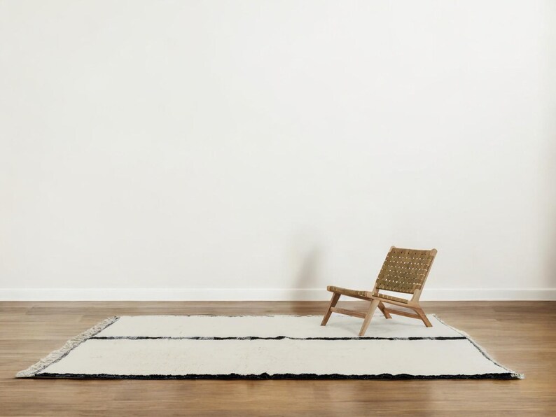 Handmade Moroccan wool rug featuring a minimalist black and white design. Ethically crafted by Berber artisans in Morocco using 100% natural wool. Thick, plush, and ultra-soft, this Beni Ourain-style carpet is perfect for modern, Scandinavian, and bohemian interiors. Ideal for living rooms, bedrooms, and luxury home decor. Available in custom sizes. Authentic tribal craftsmanship with eco-friendly materials. Free worldwide shipping with FedEx Express.