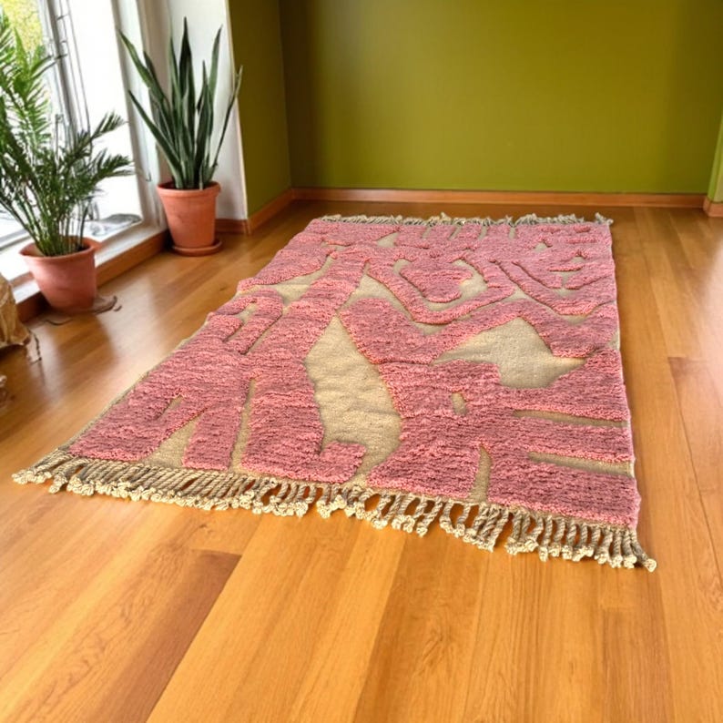 Modern abstract Moroccan Beni Mrirt rug featuring soft pink and beige tones with artistic organic patterns. Handwoven with premium wool by Amazigh artisans in Morocco. This boho-chic rug is perfect for adding an artistic touch to contemporary, minimalist, or eclectic interiors. Plush and cozy underfoot, it’s ideal for living rooms, bedrooms, and stylish creative spaces. Unique handmade piece crafted with passion and heritage.