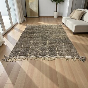 Handwoven Moroccan rug made from 100% natural wool in Travertine and White tones. Its rich texture and neutral color palette make it the perfect statement piece for modern, minimalist, or boho interiors. Crafted by Amazigh artisans in the Atlas Mountains, this rug combines traditional Moroccan weaving with a soft, earthy design. Ideal for living rooms, bedrooms, or cozy reading spaces, it brings warmth and timeless elegance to your home.