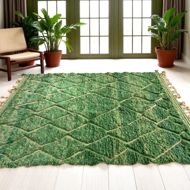 Green Moroccan wool rug with cream diamond lattice pattern, handmade in Beni Ourain style. Styled in a bright modern boho room with plants, rattan furniture, and natural light. The rug has a plush texture, tribal design, and fringe details, making it perfect for earthy, creative, or minimalist interiors. Crafted by Berber artisans, it's soft, thick, and ethically made using traditional weaving techniques.