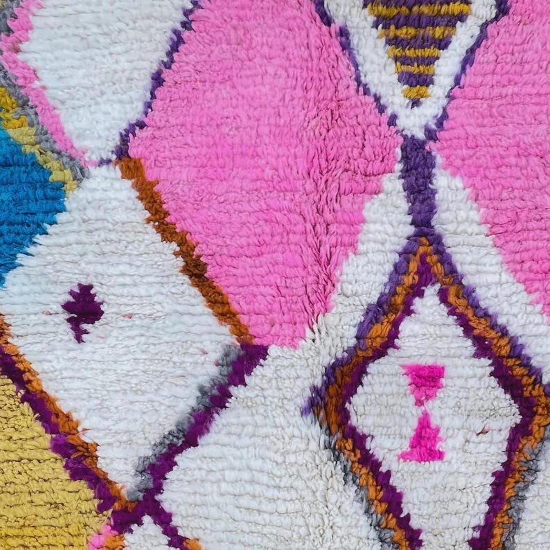 Authentic handmade Moroccan Boujaad rug featuring bold geometric diamond patterns in vibrant multicolor — electric blue, fuchsia pink, orange, yellow and purple on ivory wool background. Hand-knotted by Berber artisans in Morocco using natural wool. Perfect boho statement rug for living room, bedroom or dining room. One-of-a-kind colorful area rug with traditional fringe.