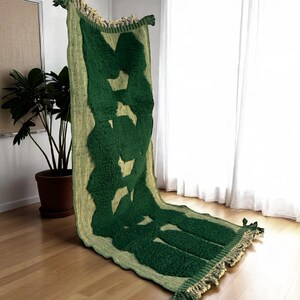 Extra-long Moroccan runner rug in deep green with bold organic patterns and beige wool base. This handcrafted Beni Ourain wool carpet is perfect for hallways, corridors, and modern interiors needing a unique, earthy touch. Made by Berber artisans using natural wool, it combines luxury softness and geometric structure. Ideal for minimalist, boho, or Japandi-style homes.