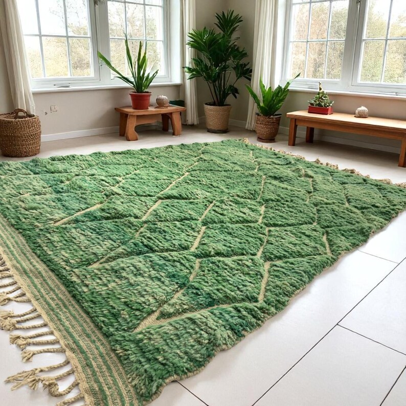 Green Moroccan wool rug with cream diamond lattice pattern, handmade in Beni Ourain style. Styled in a bright modern boho room with plants, rattan furniture, and natural light. The rug has a plush texture, tribal design, and fringe details, making it perfect for earthy, creative, or minimalist interiors. Crafted by Berber artisans, it's soft, thick, and ethically made using traditional weaving techniques.