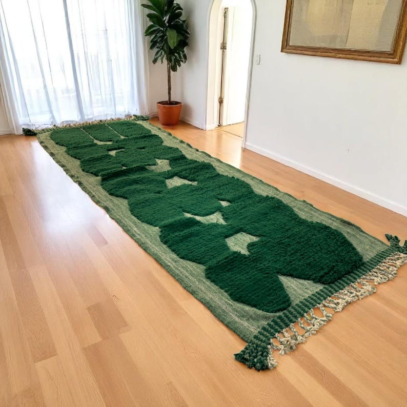 Extra-long Moroccan runner rug in deep green with bold organic patterns and beige wool base. This handcrafted Beni Ourain wool carpet is perfect for hallways, corridors, and modern interiors needing a unique, earthy touch. Made by Berber artisans using natural wool, it combines luxury softness and geometric structure. Ideal for minimalist, boho, or Japandi-style homes.