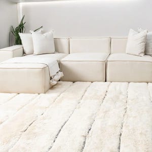 Beautiful handmade Moroccan rug in beige and black, featuring a bold geometric diamond pattern. Crafted from soft wool, it adds warmth and style to living rooms, bedrooms, or boho-chic spaces. Unique fringes enhance its artisan charm and timeless
