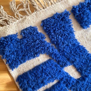 A vintage Moroccan wool rug with a bold blue abstract design handwoven on a neutral beige background, featuring plush texture and traditional fringed edges Vintage Rug, Moroccan Rug Wool Rug Abstract Rug Handwoven Rug Blue Rug Bold Design Modern Rug