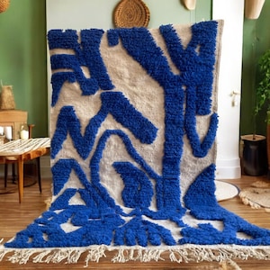 A vintage Moroccan wool rug with a bold blue abstract design handwoven on a neutral beige background, featuring plush texture and traditional fringed edges Vintage Rug, Moroccan Rug Wool Rug Abstract Rug Handwoven Rug Blue Rug Bold Design Modern Rug