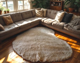 May include: A large, off-white, fluffy, heart-shaped rug in a living room with a sectional sofa and large potted plants.