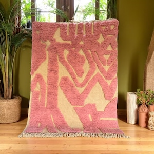 Modern abstract Moroccan Beni Mrirt rug featuring soft pink and beige tones with artistic organic patterns. Handwoven with premium wool by Amazigh artisans in Morocco. This boho-chic rug is perfect for adding an artistic touch to contemporary, minimalist, or eclectic interiors. Plush and cozy underfoot, it’s ideal for living rooms, bedrooms, and stylish creative spaces. Unique handmade piece crafted with passion and heritage.