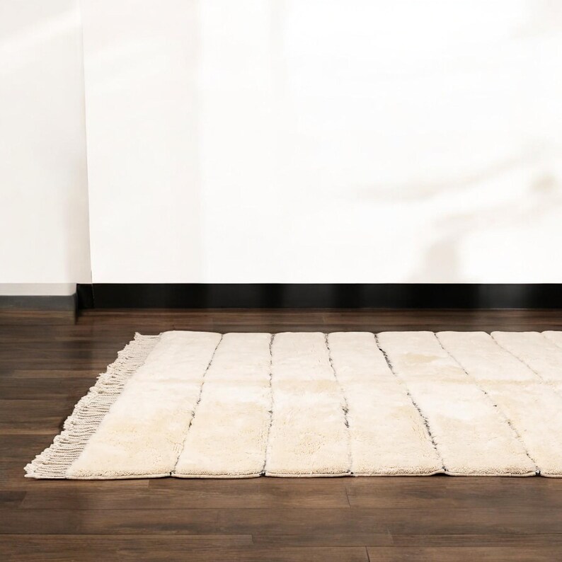 Handmade Moroccan rug with minimalist horizontal striped design, crafted from plush wool in a warm beige tone. Soft and cozy, this rug is ideal for living rooms, bedrooms, or modern spaces. Subtle fringes add a touch of traditional elegance.