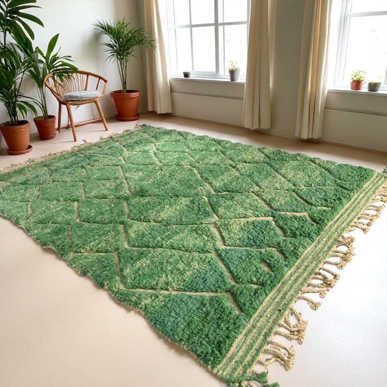 Green Moroccan wool rug with cream diamond lattice pattern, handmade in Beni Ourain style. Styled in a bright modern boho room with plants, rattan furniture, and natural light. The rug has a plush texture, tribal design, and fringe details, making it perfect for earthy, creative, or minimalist interiors. Crafted by Berber artisans, it's soft, thick, and ethically made using traditional weaving techniques.