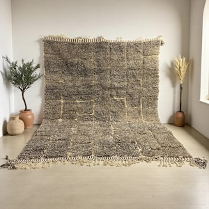 Handwoven Moroccan rug made from 100% natural wool in Travertine and White tones. Its rich texture and neutral color palette make it the perfect statement piece for modern, minimalist, or boho interiors. Crafted by Amazigh artisans in the Atlas Mountains, this rug combines traditional Moroccan weaving with a soft, earthy design. Ideal for living rooms, bedrooms, or cozy reading spaces, it brings warmth and timeless elegance to your home.