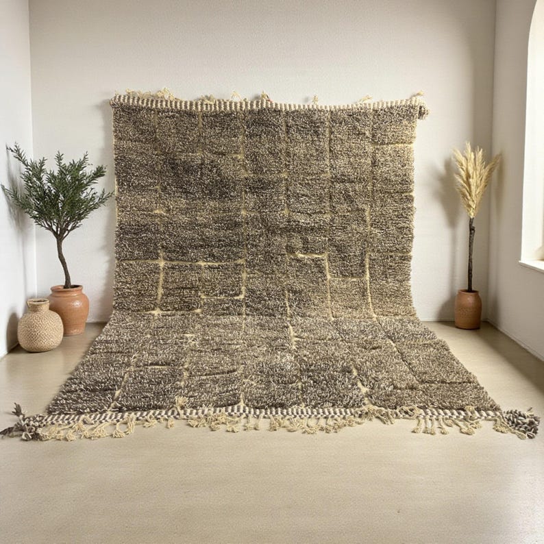 Handwoven Moroccan rug made from 100% natural wool in Travertine and White tones. Its rich texture and neutral color palette make it the perfect statement piece for modern, minimalist, or boho interiors. Crafted by Amazigh artisans in the Atlas Mountains, this rug combines traditional Moroccan weaving with a soft, earthy design. Ideal for living rooms, bedrooms, or cozy reading spaces, it brings warmth and timeless elegance to your home.
