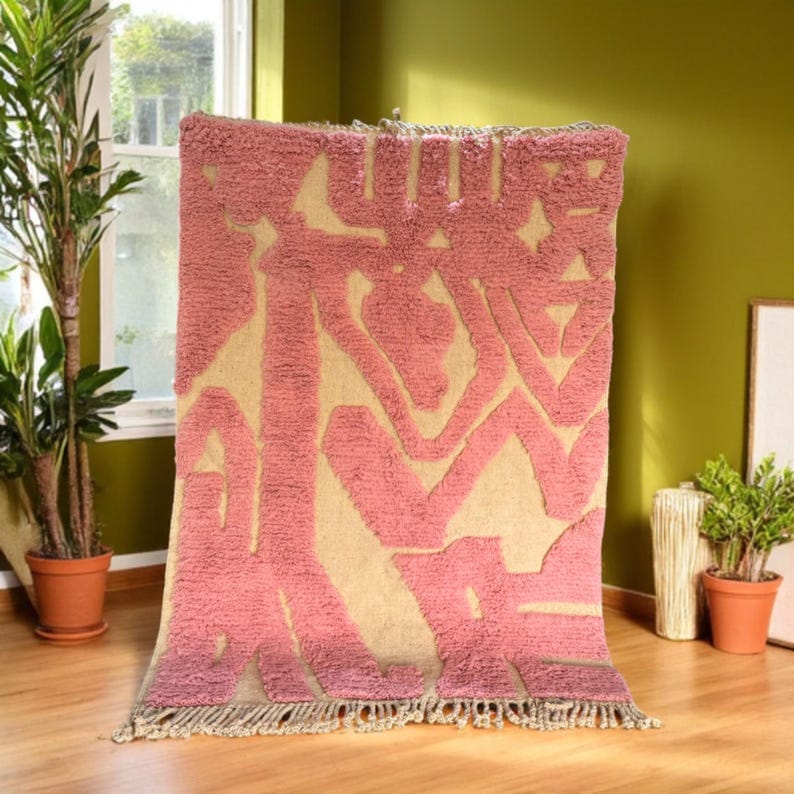 Modern abstract Moroccan Beni Mrirt rug featuring soft pink and beige tones with artistic organic patterns. Handwoven with premium wool by Amazigh artisans in Morocco. This boho-chic rug is perfect for adding an artistic touch to contemporary, minimalist, or eclectic interiors. Plush and cozy underfoot, it’s ideal for living rooms, bedrooms, and stylish creative spaces. Unique handmade piece crafted with passion and heritage.