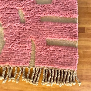 Modern abstract Moroccan Beni Mrirt rug featuring soft pink and beige tones with artistic organic patterns. Handwoven with premium wool by Amazigh artisans in Morocco. This boho-chic rug is perfect for adding an artistic touch to contemporary, minimalist, or eclectic interiors. Plush and cozy underfoot, it’s ideal for living rooms, bedrooms, and stylish creative spaces. Unique handmade piece crafted with passion and heritage.