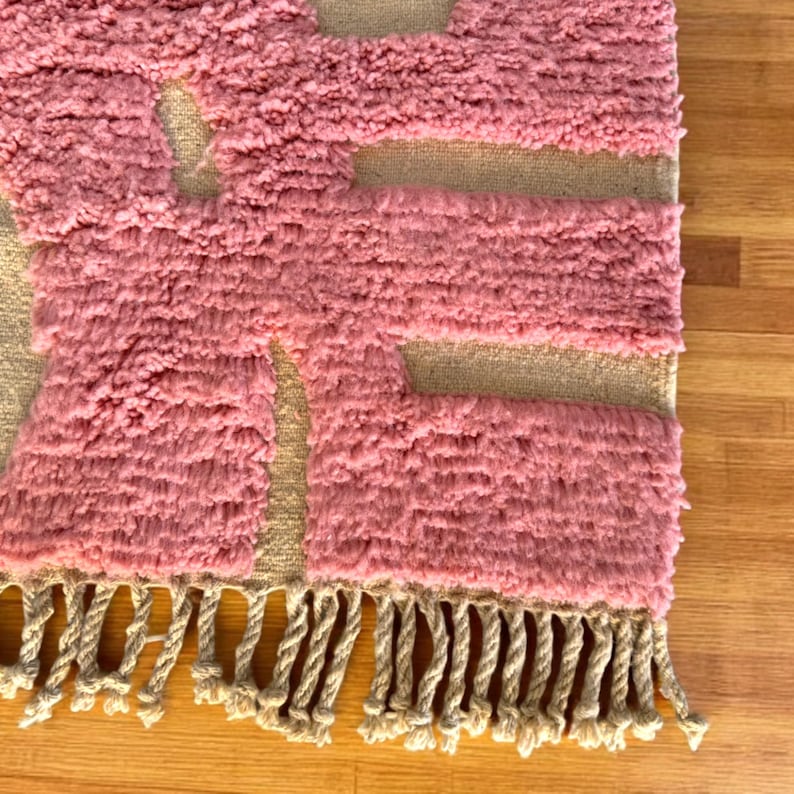 Modern abstract Moroccan Beni Mrirt rug featuring soft pink and beige tones with artistic organic patterns. Handwoven with premium wool by Amazigh artisans in Morocco. This boho-chic rug is perfect for adding an artistic touch to contemporary, minimalist, or eclectic interiors. Plush and cozy underfoot, it’s ideal for living rooms, bedrooms, and stylish creative spaces. Unique handmade piece crafted with passion and heritage.