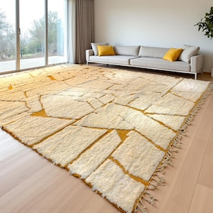 Handmade Moroccan rug in a soft ivory base with striking mustard yellow (Thai Curry) abstract lines. Woven by Berber artisans in pure wool, this rug blends tradition and modern style. Its geometric tribal pattern and warm tones make it perfect for living rooms, bedrooms, or creative interiors. Durable, eco-friendly, and soft underfoot, this ivory and mustard Berber carpet adds Moroccan charm and luxury to boho, modern, or eclectic home decor.